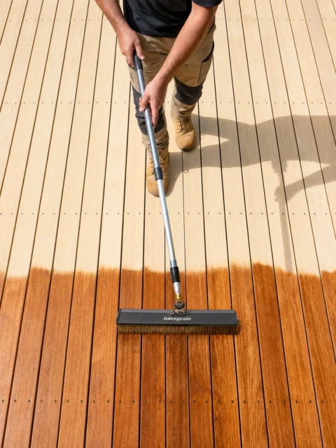 A worker applying penetrating oil to a timber deck